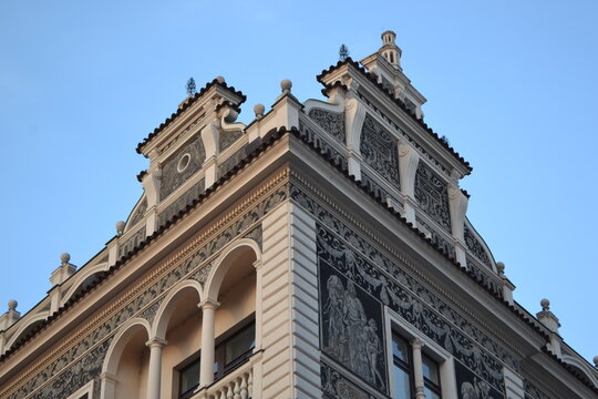 Detailed ornate upper facade with sgraffito murals and arched balcony for Prague architectural background and heritage poster
