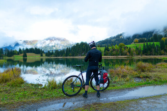 Cyclist Photographing Lake Lauenen with Cloud-Covered Mountains near Gstaad, Switzerland