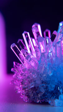 A real crystal. The grown crystal rotates on an illuminated turntable. A scientific experiment and chemical study. A beautiful background or screensaver. Pink and blue.