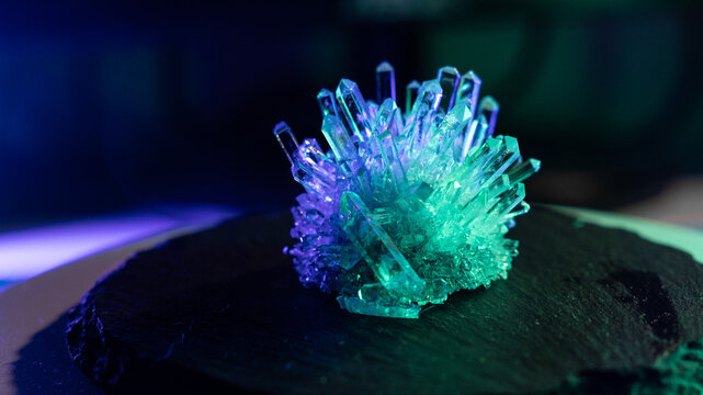A mysterious, magical, genuine crystal. A grown crystal on a rotating, illuminated stand. A scientific experiment and chemical study. A beautiful background or screensaver. Blue and green.