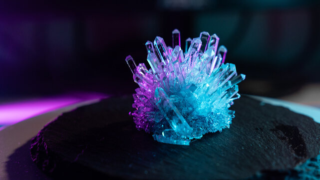 A mysterious, magical, genuine crystal. A grown crystal on a rotating, illuminated stand. A scientific experiment and chemical study. A beautiful background or screensaver. Purple and blue.