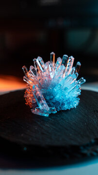 A mysterious, magical, genuine crystal. A grown crystal on a rotating, illuminated stand. A scientific experiment and chemical study. A beautiful background or screensaver. Orange and blue.