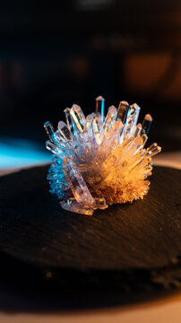 A mysterious, magical, genuine crystal. A grown crystal on a rotating, illuminated stand. A scientific experiment and chemical study. A beautiful background or screensaver. Orange and blue.