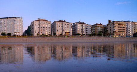 Obraz premium Sunset over Zurriola beach with city reflection on wet sand, San Sebastian, Basque Country, Spain
