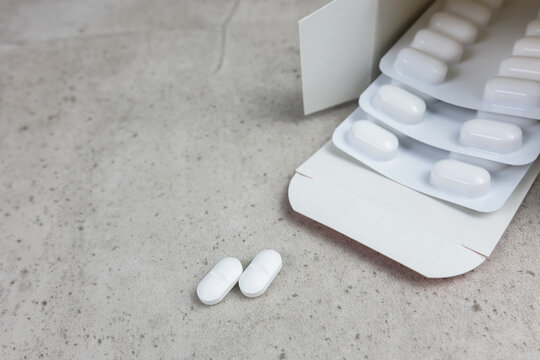 White pills and cardboard box on the stone background with place for text.