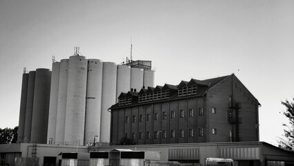 old factory building , Industrial grain silos next to a historic brick warehouse building, black and white architectural landscape © 4till4
