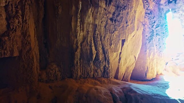 Golden sunrise light shines into the natural sandstone slot cavern of Goblette Lair at Goblin Valley State Park in Utah