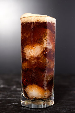 Misted cool glass with a glass of Coke, Pepsi, rum, alcohol ice cubes on a black background