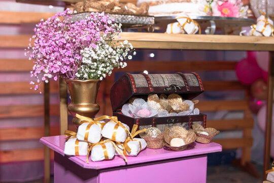 Vintage wooden chest filled with sweets next to traditional bem casado favors and purple flowers