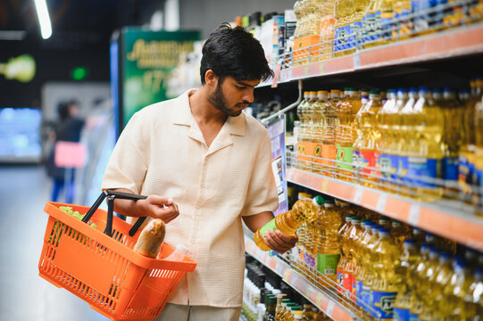Indian man shopping cooking oil in supermarket aisle