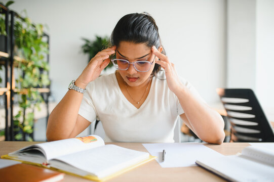 Stressed indian female student experiencing headache studying
