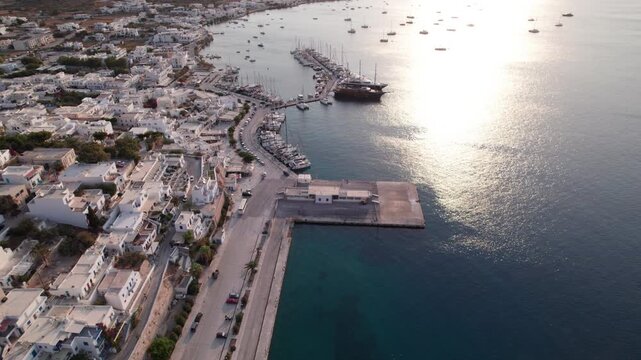 Views of Naxos town and harbor at sunrise over Paros island with white buildings and blue church beside the Aegean Sea
