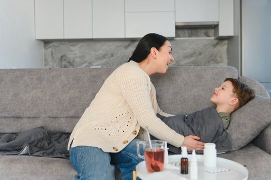 Mother caring for sick child on sofa at home
