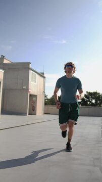 Vertical screen determined young man runs outdoors staying committed to fitness regardless of conditions building discipline endurance and consistency through daily training
