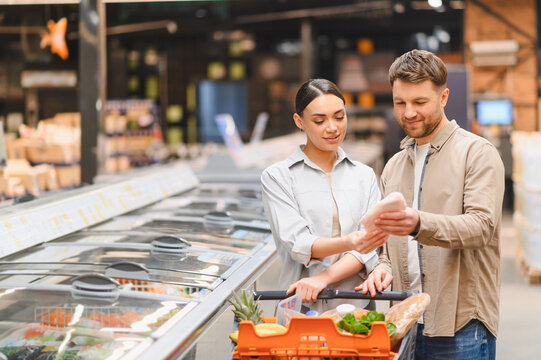 Happy couple choosing frozen food in supermarket freezer aisle
