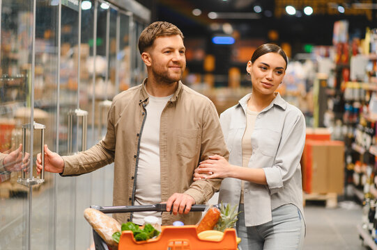 Couple shopping for groceries at supermarket refrigerator