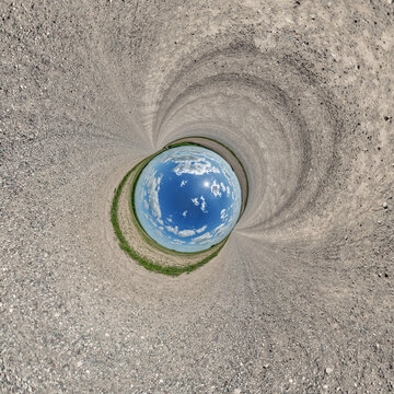 creative tiny planet photo of a rural landscape with dirt road, green fields, and cloudy sky forming a circular world.