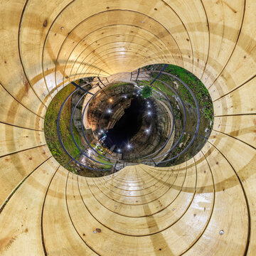 creative tiny planet photo of a rural landscape with dirt road, green fields, and cloudy sky forming a circular world.