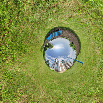 creative tiny planet photo of a rural landscape with dirt road, green fields, and cloudy sky forming a circular world.