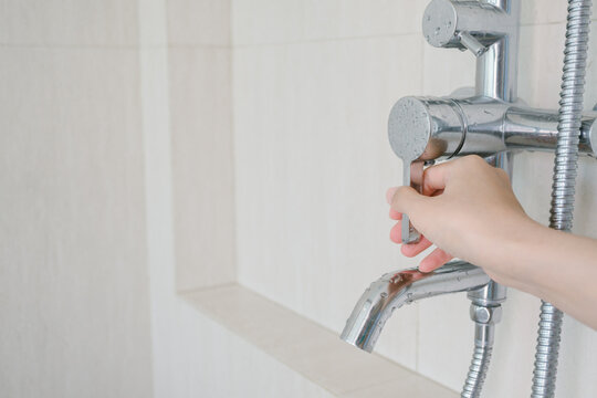 Close up hand turning faucet handle metal shower control valve adjustment feeling calm and relaxed while preparing for daily bathing