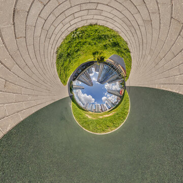 creative tiny planet photo of a rural landscape with dirt road, green fields, and cloudy sky forming a circular world.