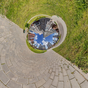 creative tiny planet photo of a rural landscape with dirt road, green fields, and cloudy sky forming a circular world.