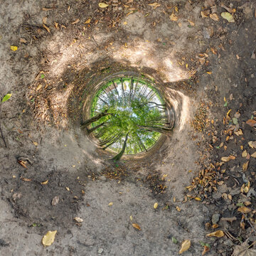 creative tiny planet photo of a rural landscape with dirt road, green fields, and cloudy sky forming a circular world.
