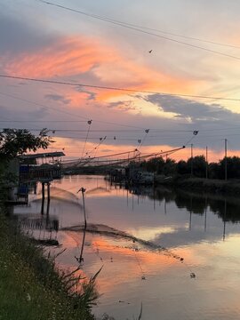 Tramonto sulle Valli di Comacchio con riflesso sull'acqua e bilancioni da pesca, Delta del Po