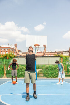 vertical Young multicultural man celebrating victory on basketball court