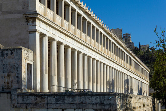 Stoa of Attalos colonnade showcasing Doric and Ionic orders, reconstructed ancient Greek architecture standing against a clear blue sky, with the Acropolis visible in the background