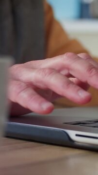 Senior person typing on laptop at home