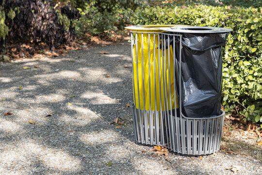 Outdoor waste bins with yellow and black bags and copy space