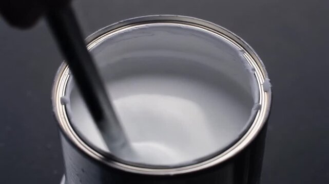 Stirrer turning in a tin of white paint