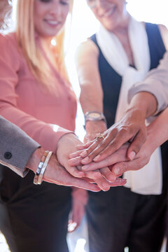 Smiling diverse businesswomen stacking hands in a team unity gesture