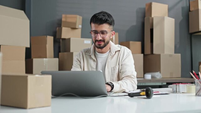 Young man works with laptop in warehouse