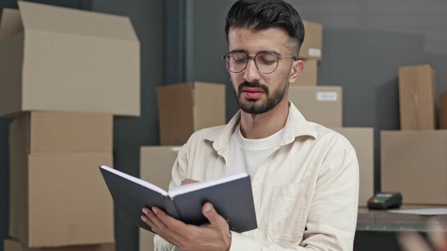Man reads notes at desk with pencils nearby