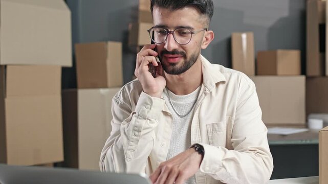 Man speaks on phone while working at desk
