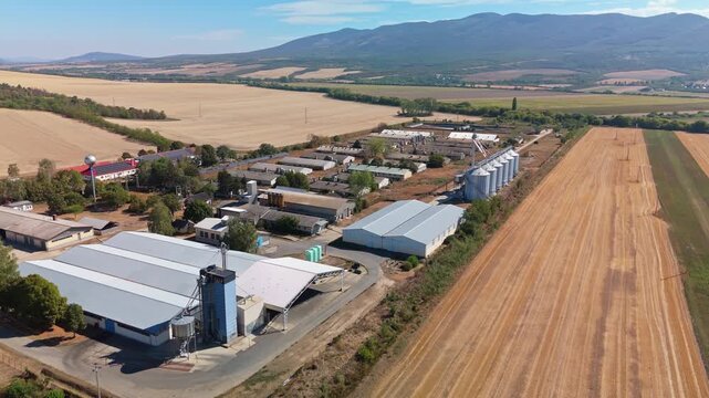 P&aacute;szt&oacute;, Hungary feed mill with silos, barns and grain storage beside summer fields and hills in N&oacute;gr&aacute;d County, rural agricultural infrastructure and livestock feed production, drone view