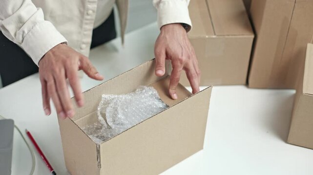 Hands unwrap bubble wrap from a cardboard box