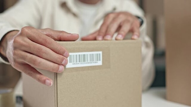 Person seals a cardboard box with clear tape