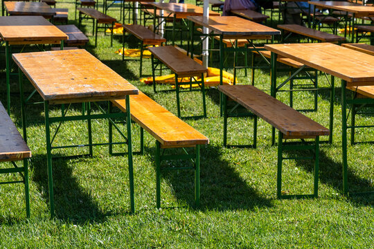 Empty wooden benches and tables arranged on grass at outdoor event