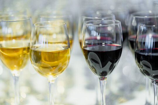 Red and white wine portions fill an arrangement of stemmed drinking glasses, showing prepared beverage service for banquets, social functions and catered events