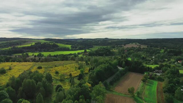 Panorama z wysokości wykonana przy użyciu zmieniającego położenie drona. Pofałdowany teren na Przedg&oacute;rzu Sudeckim, pokryty łąkami, polami uprawnymi i lasami.  