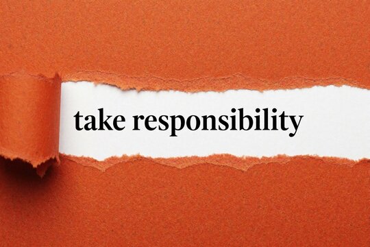 Torn orange paper reveals white background with black text saying take responsibility. Concept for ownership accountability and personal growth.