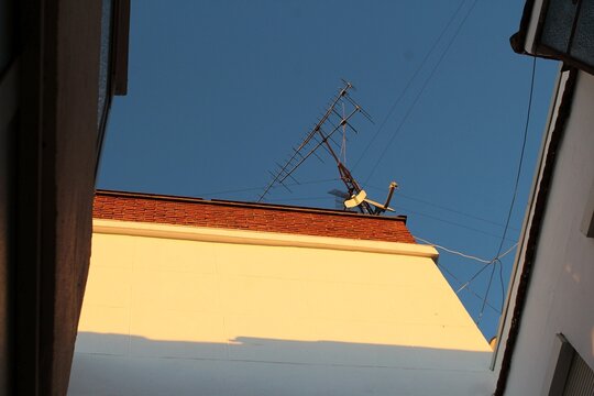 Antena de televisi&oacute;n antigua sobre el tejado de un edificio con cielo azul despejado