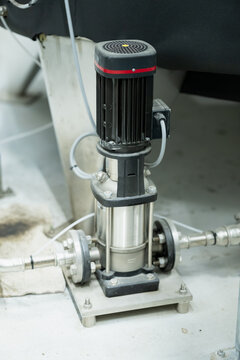 An upright motor driven pump stands on a bolted base between inlet and outlet piping, showing the drive assembly and fluid connections of a utility pumping installation