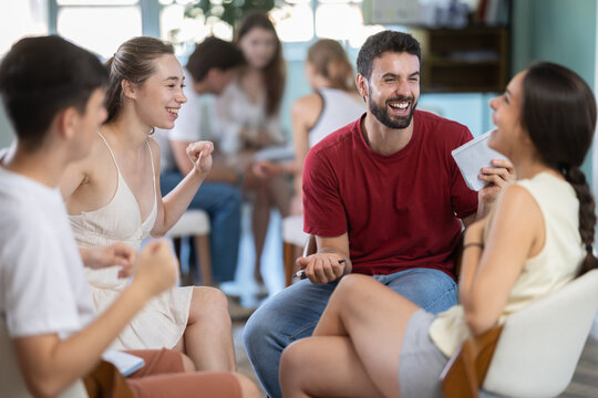 Group of participants celebrates victory in game, colleagues sit in circle and rejoice at victory