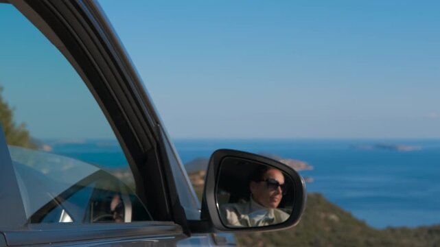 Woman enjoying a scenic coastal car ride. Beautiful woman in sunglasses looking out of a car window, enjoying the stunning seaside view during a sunny road trip