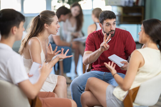 Young men and women sit in opposing teams, talking during lively group discussion session