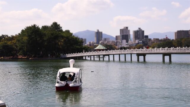 Ohori Park panorama in Fukuoka, Japan, Chuo-ku ward, Kyushu island, with pond, Ukimi-do pavilion, bridges and city skyline near Maizuru Park, lake and promenade in a spring sunny day